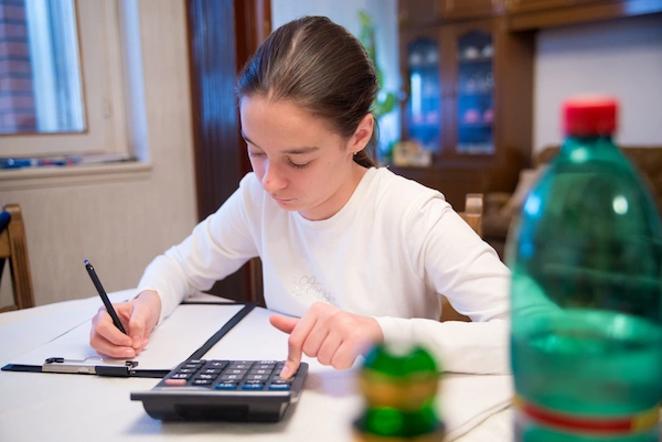 Student calculating a math problem at home at her dinner table